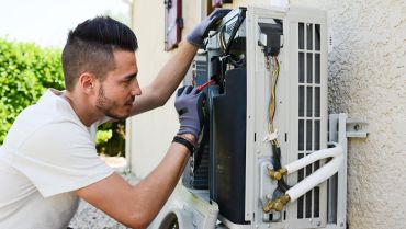 A man working on an air conditioner unit.