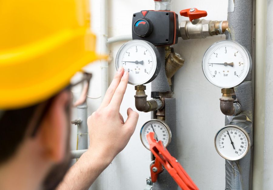 A person in yellow hard hat adjusting some gauges.