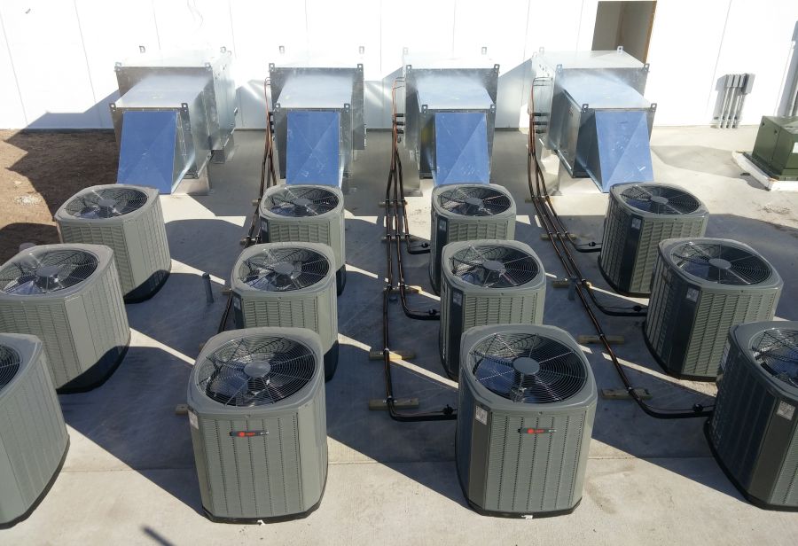 A bunch of air conditioners sitting on top of concrete.