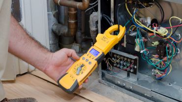 A person holding an electrical meter in their hand.